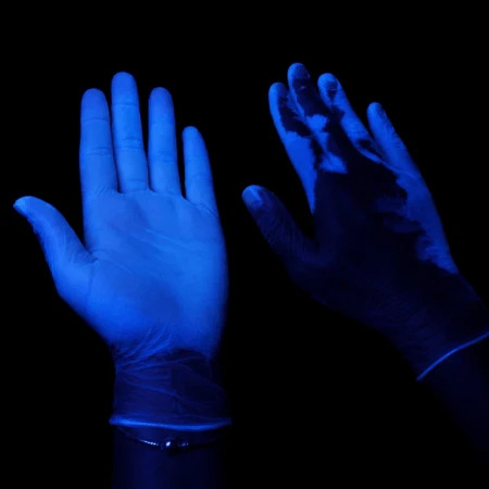 Mains sous lumière UV révélant les zones mal désinfectées avec additif UV bleu